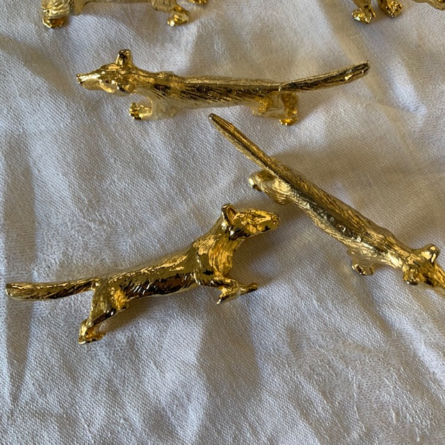 Cinq porte couteaux en métal doré, en forme de bassets ou corgis