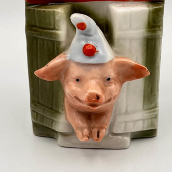 Tirelire cochon représentant un petit cochon en pyjama dans sa maison de bois